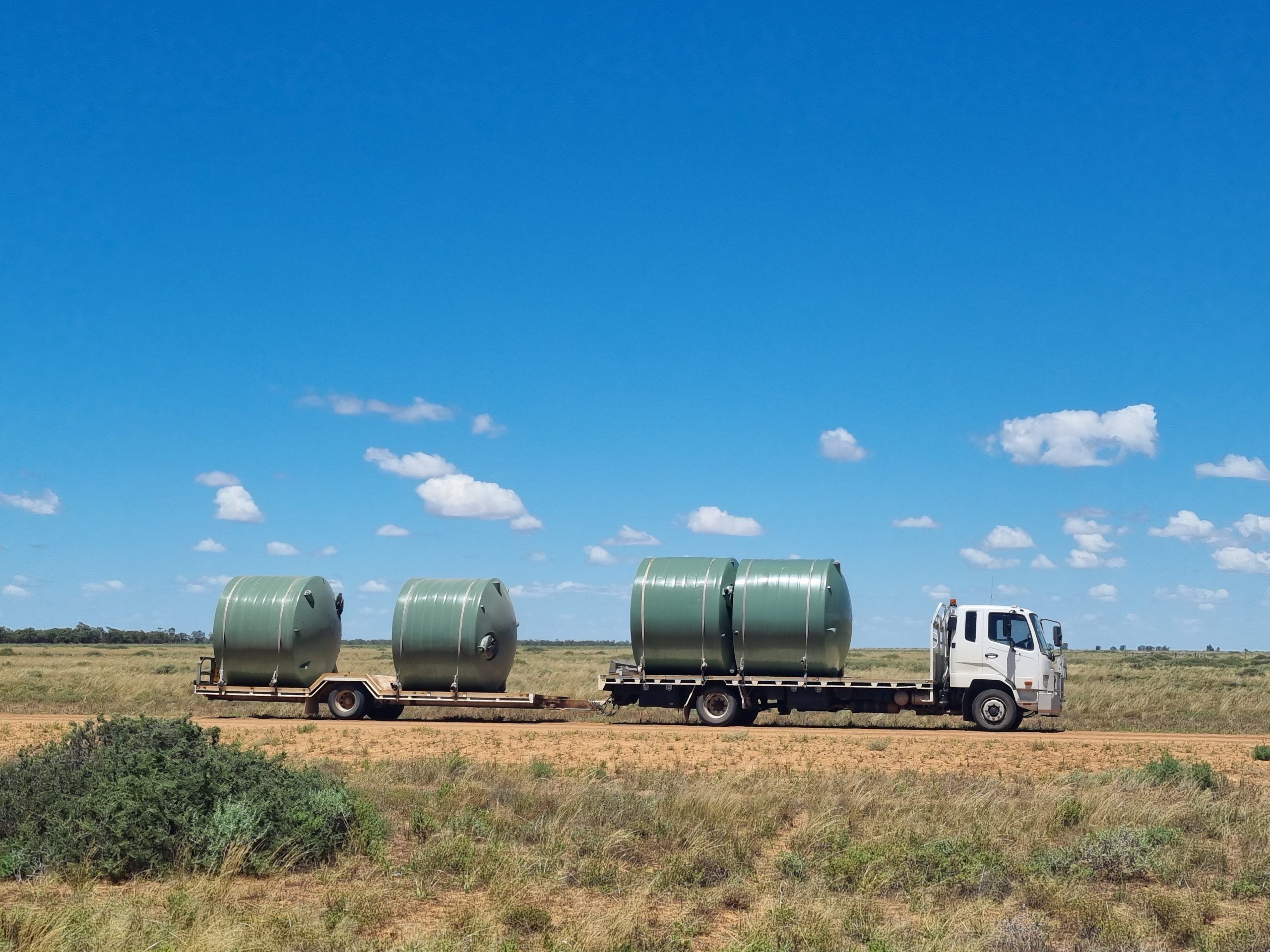 4 10,000ltr Round Poly Water Tanks in Rivergum Green on board a delivery tank truck in outback Australia